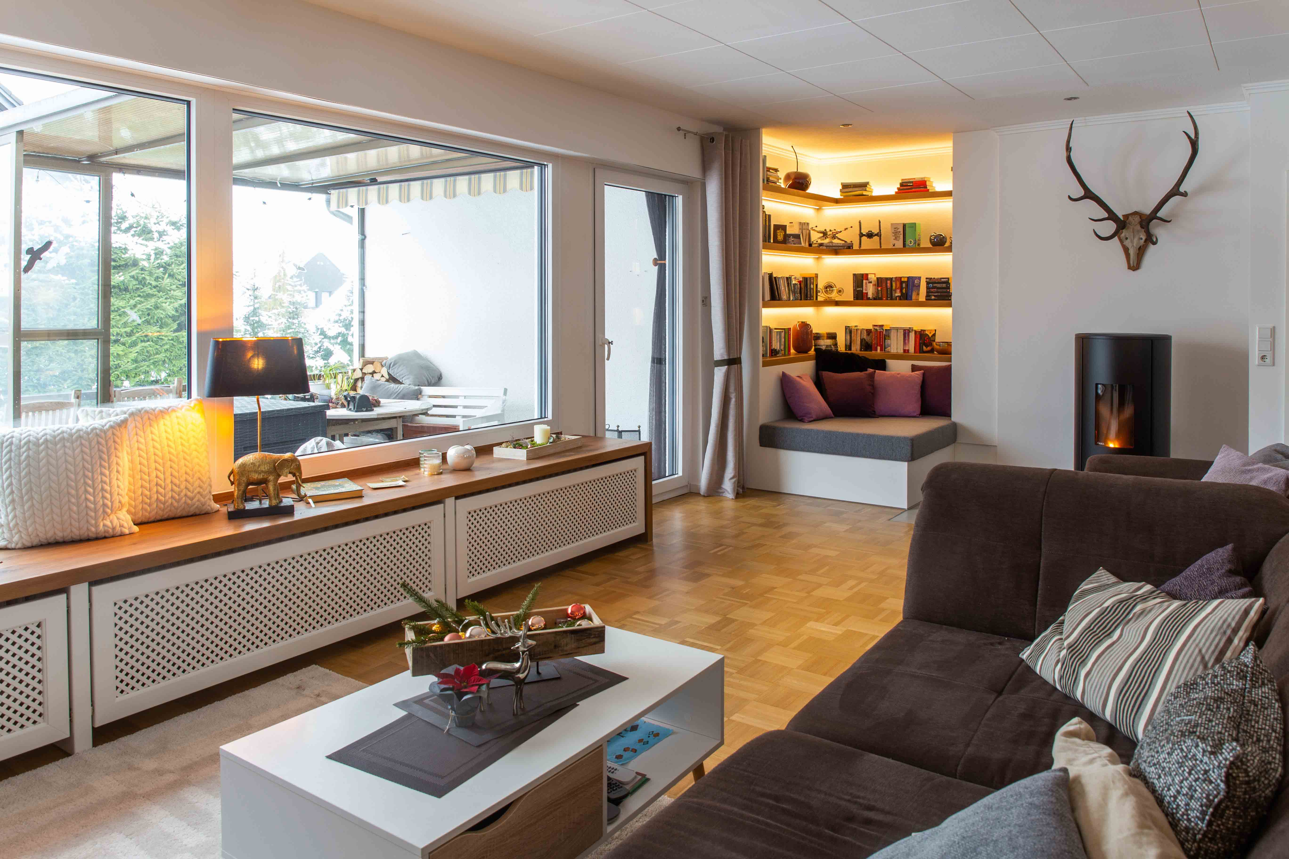 Wohnraum mit maßgefertigten Möbeln, integrierter Sitzbank und beleuchteten Regalen