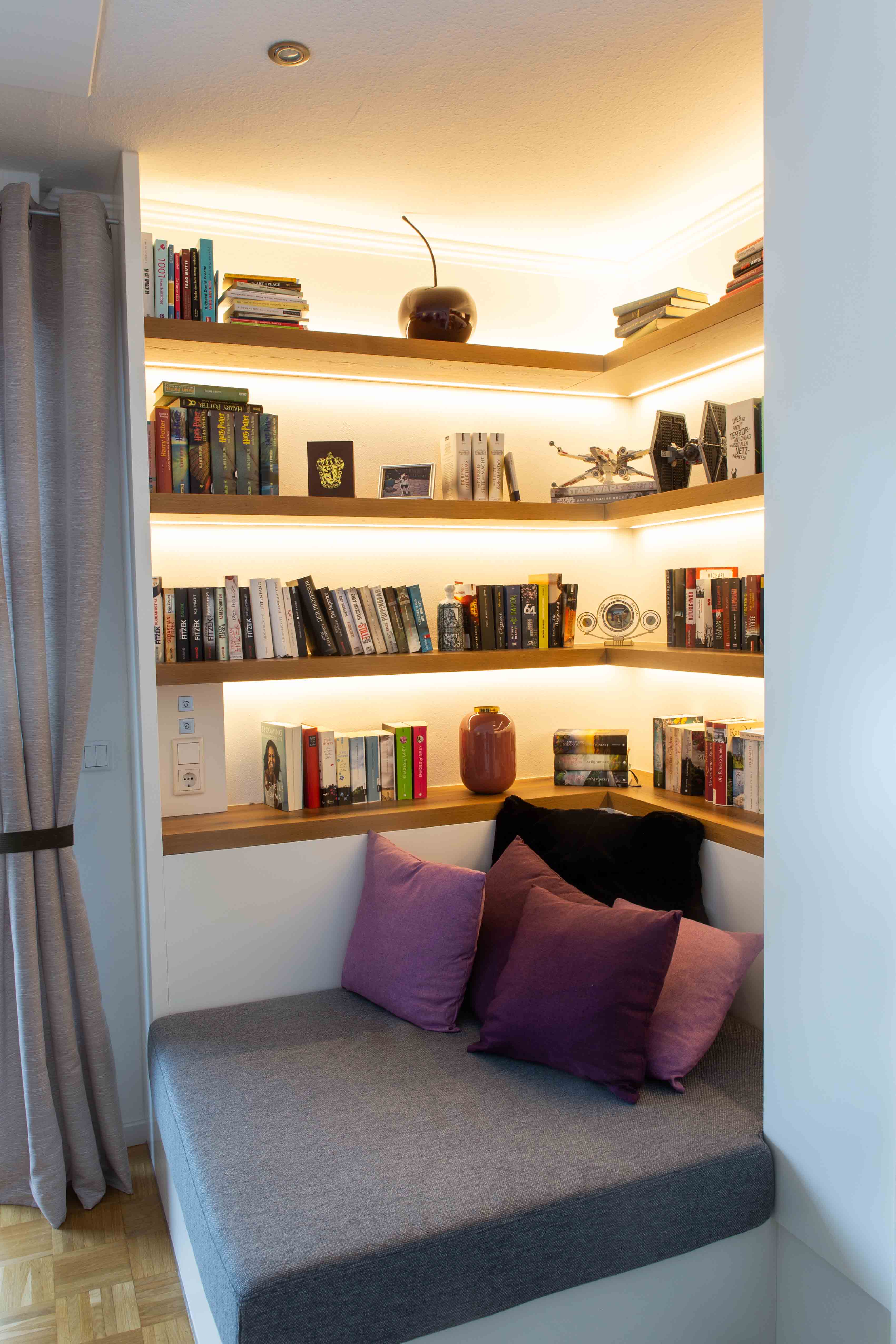 Gemütliche Leseecke mit Einbausitzbank, Holzregalen und indirekter Beleuchtung