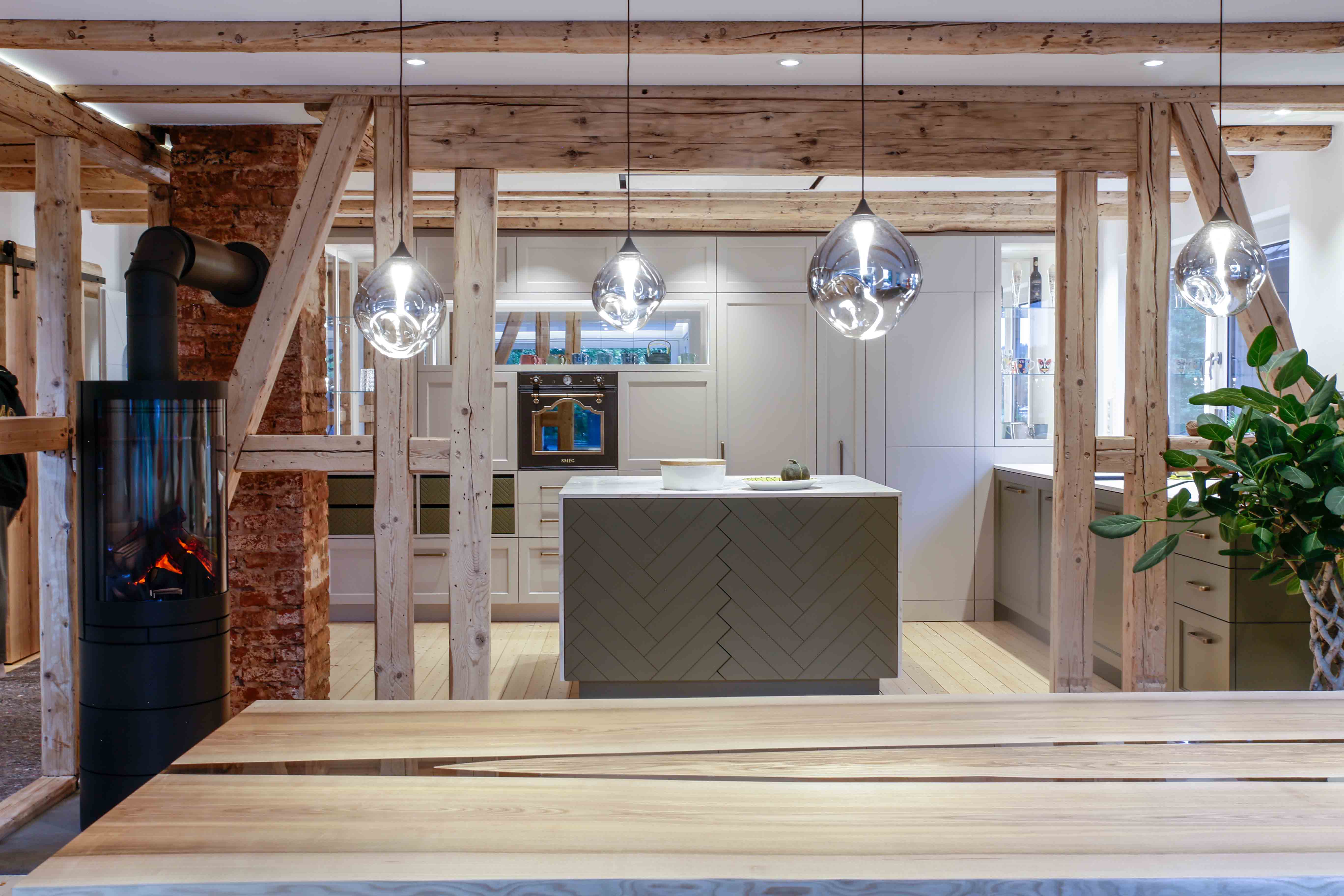 Traditionelle Küche mit sichtbaren Holzbalken, Kücheninsel und modernen Pendelleuchten im Innenausbau