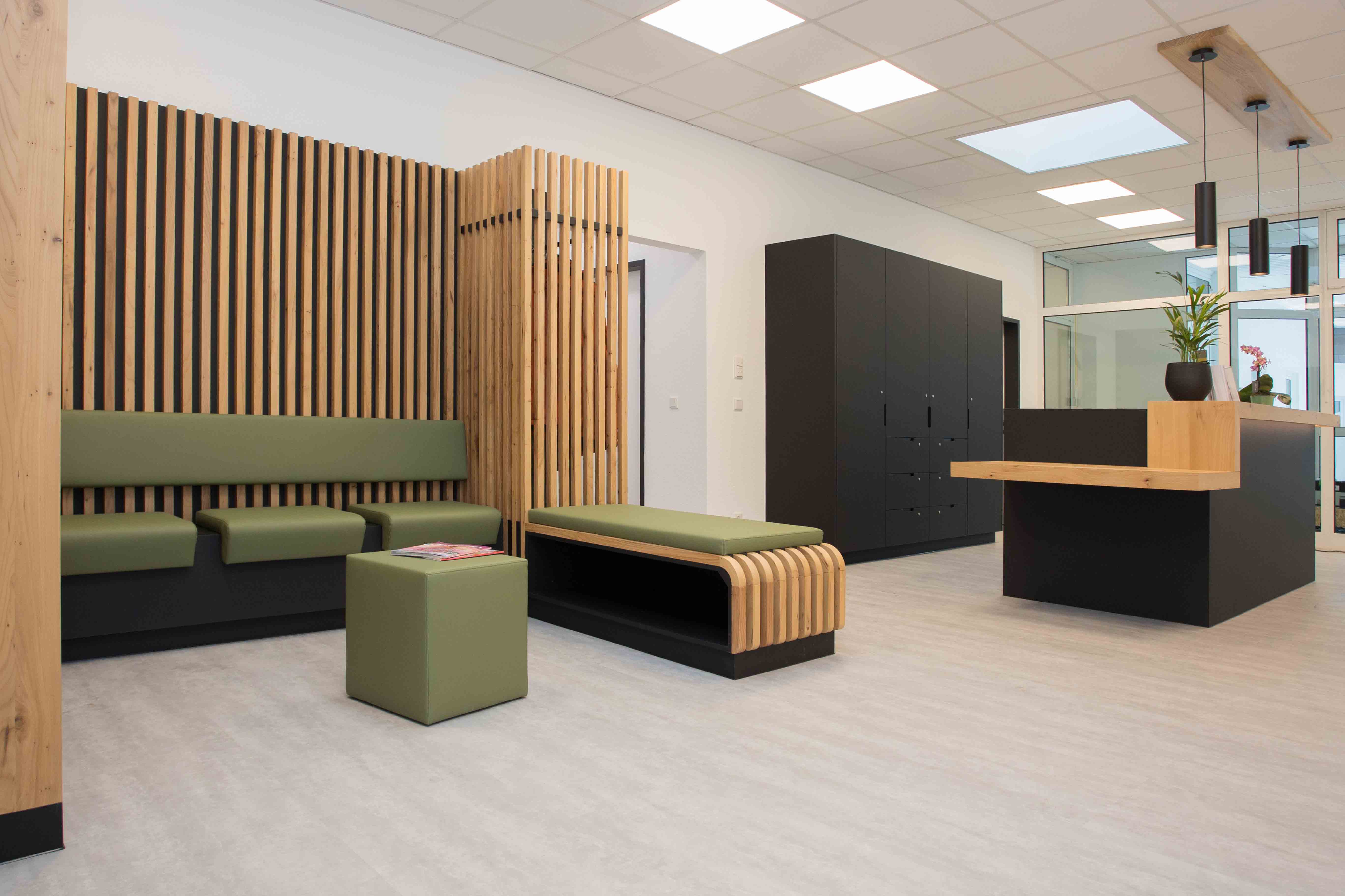 Empfangsbereich mit Sitzmöbeln aus Holz und Polstern, Lamellenwand und klarer Linienführung im Objektbau