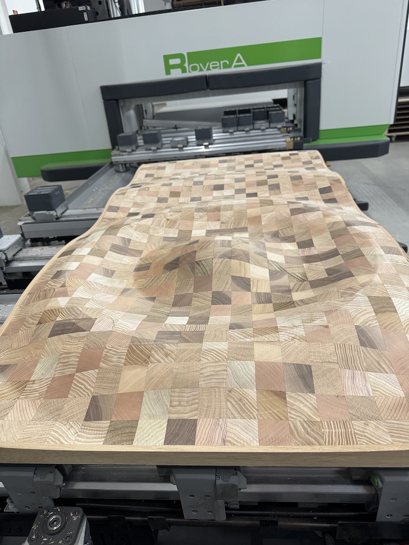 Fünfachs-CNC-Maschine bearbeitet eine massive Holzplatte mit geometrischem Muster