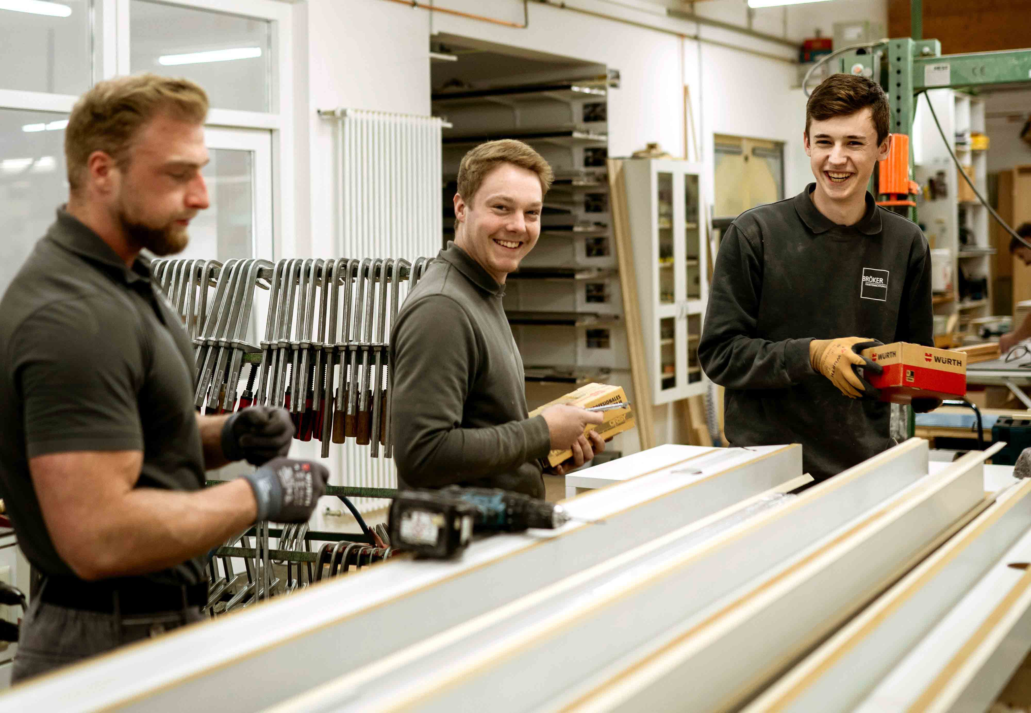 Drei Mitarbeitende montieren Bauteile und arbeiten gemeinsam an einem Werkstück